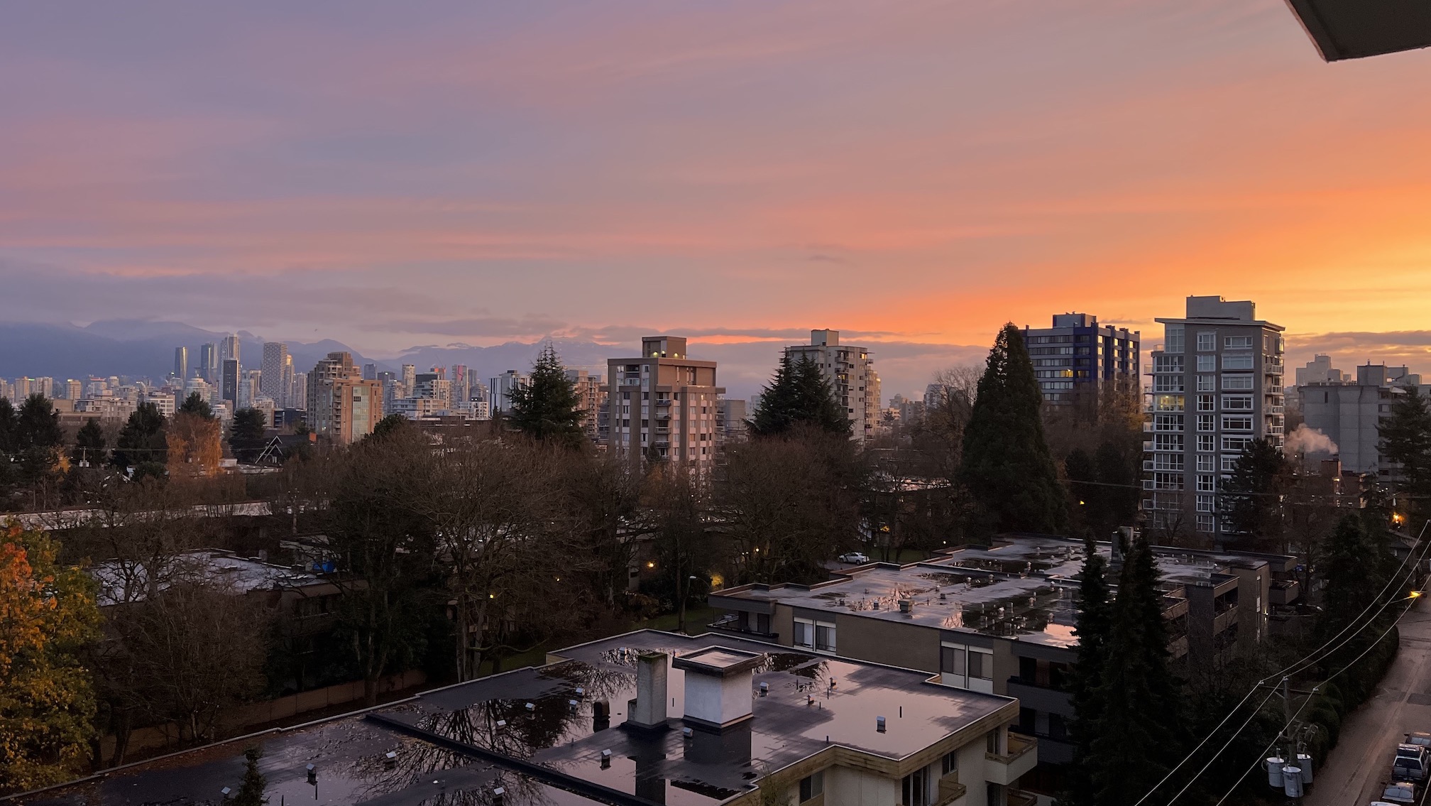 The Vancouver skyline, during a sunrise, with the mountains faintly visible in the background